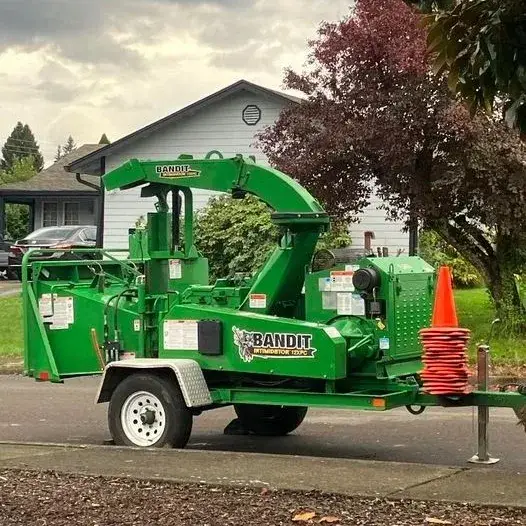 Green Bandit wood chipper used in tree service for processing branches and debris.